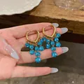 Detailansicht goldener Herz-Creolen mit hängenden, blau facettierten Perlenanhängern - Herzmanschetten-Quasten-Stil (HE33359) / Ohrring-Manschette - Blau