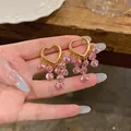Nahaufnahme von goldenen Herz-Ohrringen mit baumelnden rosa facettierten Perlen im Café - Herzmanschetten-Quasten-Stil (HE33359) / Ohrclip-Rosa
