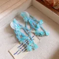 Close-up detail shot of bohemian blue resin flower tassel earrings on vintage tag - Blue