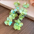 Vista dettagliata di lunghi orecchini a nappa con petali verde chiaro iridescenti e perle - Verde