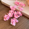 Dettaglio degli orecchini a nappa con fiori di paillettes iridescenti rosa su un libro - Rosa