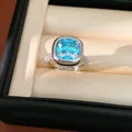 Elegante anello in argento con zircone blu a taglio cuscino e una fascia con pavé - Moissanite Blu Mare
