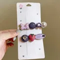 Detailed view of hair clips with strawberry, pearl, and bow charms on display card - Duckbill Hair Clips / 2 Pcs/Set / Purple