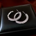 Primo piano dettagliato di orecchini a cerchio a C argentati con pietre di zircone - Stile Cerchio a C / Argento
