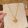 Gros plan d'un collier pendentif nœud doré sur du papier texturé rustique - Or