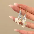 Close-up detail of Bohemian style blue beaded earrings with white shell and crystal charms - Silver Post-Gold-White-Blue