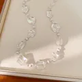 Vista dettagliata di perle di cristallo sfaccettate a forma di cuore su una collana chic - Collana clavicola lunga / Bianco