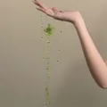 Dettaglio di una collana in perline di vetro verdi con fiore fatto a mano e nappe eleganti - Collana / Verde