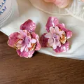 Dettaglio dei orecchini a fiore in smalto rosa con petali di stoffa su tessuto - Viola-Rosa