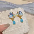 Detailed close-up of French vintage clip-on earrings with blue crystals and teardrop beads - One Pair / Gold-Blue