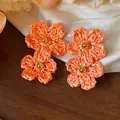 Detailed view of handmade orange raffia flower earrings with golden bead centers - Silver Post (HE31601) / Orange