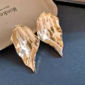 Detailed view of gold leaf earrings with a chic crumpled metal texture and glossy finish - Wrinkled Leaf Studs / Gold
