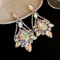 Close-up of iridescent teardrop crystal earrings with shimmering rhinestone detail. - Silver