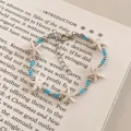Detailed macro view of a stylish blue and white starfish beaded bracelet resting on a vintage book - Silver-White-Blue
