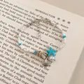 Macro view of ocean themed blue shell and starfish beaded bracelet on book page - Silver-Blue