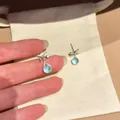 Detailed view of these light blue zircon drop earrings with an elegant silver bow design - Silver (Sea Blue)