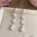 Dettaglio ravvicinato di orecchini pendenti con perle barocche irregolari - Argento
