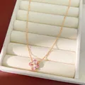 Detalle de un collar de oro rosa con un colgante de flor de circón rosa en un estuche. - Collar / Rosa