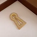 Detailed macro shot of a vintage gold-toned keyhole brooch with brilliant zircon pave setting - Zirconia Keyhole Style (Gold)