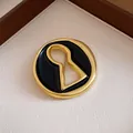 Detail shot of a vintage gold-plated keyhole brooch with black enamel finish for women - Round Keyhole Style (Black)