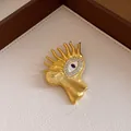 Close-up of a surrealist gold eye brooch featuring radiant flame-like rays and zircons - Evil Eye Style (Gold)