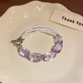 Vista dettagliata del bracciale a più fili di perle e perle di cristallo viola su un piatto. - Viola e Bianco
