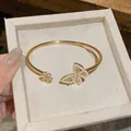 Detailed macro shot of golden butterfly open bangle with white pearls and sparkling zircons - Gold