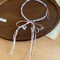Detail view of sweet pink bow beaded necklace with white lily-of-the-valley charms on tray - Pink