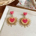 Primo piano di orecchini a cuore retrò con motivo a raggiera e smalto rosa vibrante. - Rosa Rosso