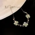 Primo piano di un elegante bracciale a quadrifoglio con pietra occhio di gatto e strass lucenti - Bracciale a Fiore / Verde