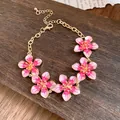 Dettaglio dei fiori in smalto rosa su un bracciale in metallo dorato vintage - Rosa