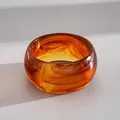 Primo piano di bracciale rigido in acrilico ambrato con texture marmorizzata retrò - Ambra