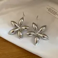 Nahaufnahme glänzender silberner Blumen-Ohrstecker mit edler Metallreflexion. - Blumenstil (HE32273) / Silber