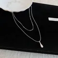 Close-up view of a double-layered silver necklace featuring a sleek teardrop pendant - Double Layer Necklace with Teardrop Pendant / Silver