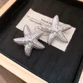 Primo piano di orecchini a lobo a forma di stella marina argentata con perle e trama. - Argento-Bianco