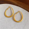 Primer plano de pendientes de aro dorados en forma de lágrima con elegante acabado mate - Estilo Gota de Agua Esmerilado (HE33967)