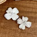 Dettaglio di eleganti orecchini a fiore con perline bianche su sfondo di legno - Orecchini(HE31938) / Bianco