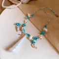 Detail view of a ocean-style necklace with starfish and turquoise beads on a beige surface - Blue