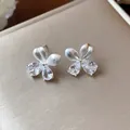 Gros plan de boucles d'oreilles fleurs avec zircones en goutte et pétales argentés mats. - Argent (Tige en argent)