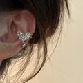 Close-up of a silver heart-shaped ear cuff with sparkling zircon and cross detail - Ear Bone Clip (Single) / Silver