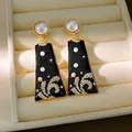 Close-up of vintage black enamel drop earrings with pearls and rhinestones in jewelry box. - Dangle Type / Black