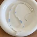 Detailed view of beaded necklace with blue crystals, white pearls, and zircon pendant. - Choker Necklace / Silver