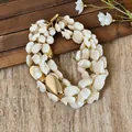 Zoom sur un collier imposant en coquillage blanc avec accents dorés, style luxe de vacances. - Blanc