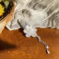 Detailed view of an elegant floral hair clip with pearlescent petals and pearl tassels. - White