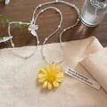 Detailansicht eines gelben Blumenanhängers an einer Perlen- und Glasperlenkette. - Gelb