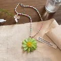 Detailansicht einer bunten Perlenhalskette mit einem großen grünen Blumenanhänger. - Grün