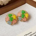 Macro view of vintage style colorful resin round stud earrings with pearls and gold-tone finish - Floral Round Style / Gold/Multicolor