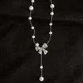 Élégant collier de perles en Y avec pendentif nœud serti de CZ sur fond noir texturé - Argent-Rose