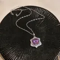 Close-up of a purple zircon pendant necklace with a vintage palace design on a black plate. - Round Halo Hexagonal Star (HN11764)