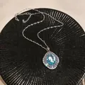 Detailed macro shot of a vintage light blue zircon necklace on a textured black plate. - Oval Baguette Inlaid Style (HN11764)